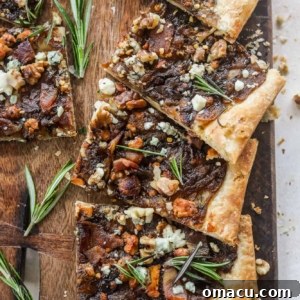 Caramelized Onion Puff Pastry with bacon and gorgonzola on a cutting board with rosemary leaves