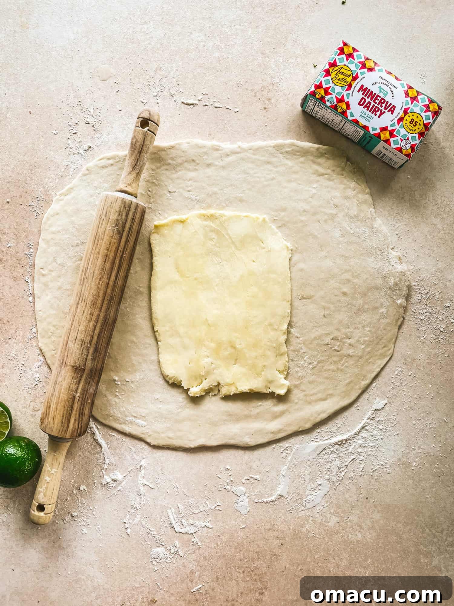 A block of butter placed precisely in the center of the rolled-out puff pastry dough.