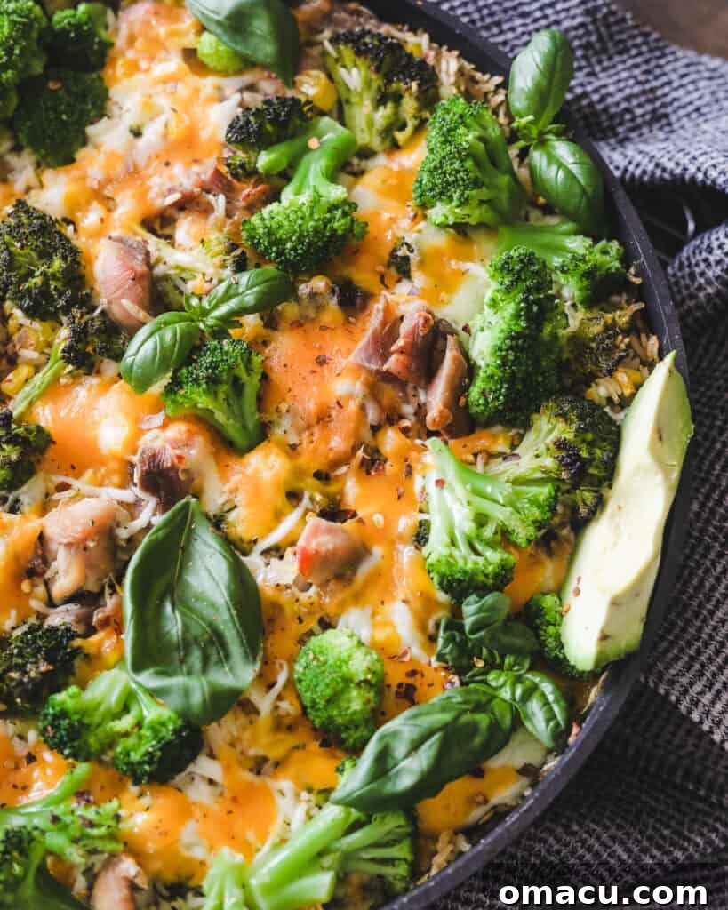 Overhead shot of the cooked Easy Chicken Broccoli Rice and Cheese Casserole in a skillet, topped with melted cheese and fresh basil.