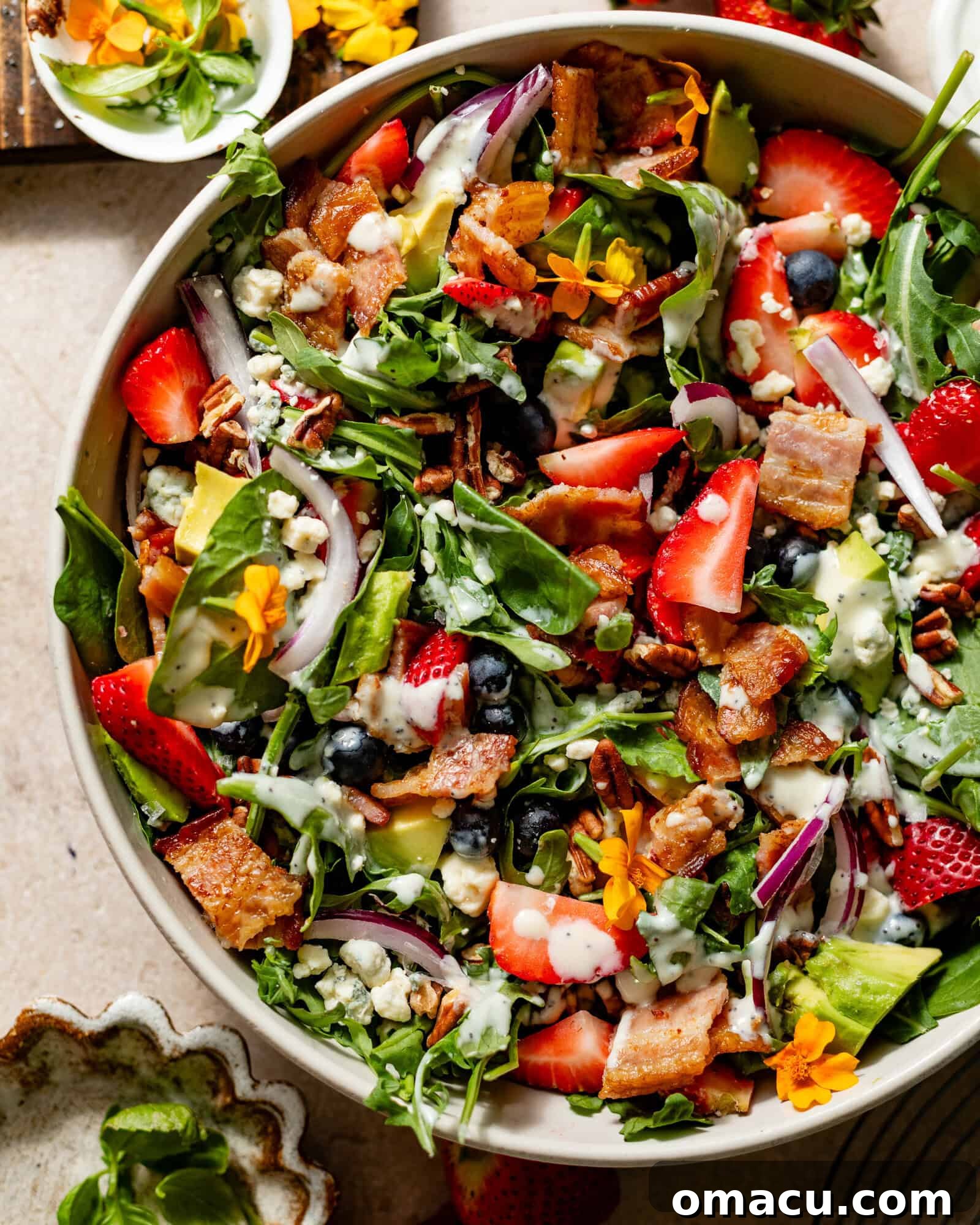 A large, beautifully prepared strawberry spinach salad in a serving bowl, showcasing vibrant arugula and crumbled gorgonzola cheese as toppings, ready to be enjoyed.