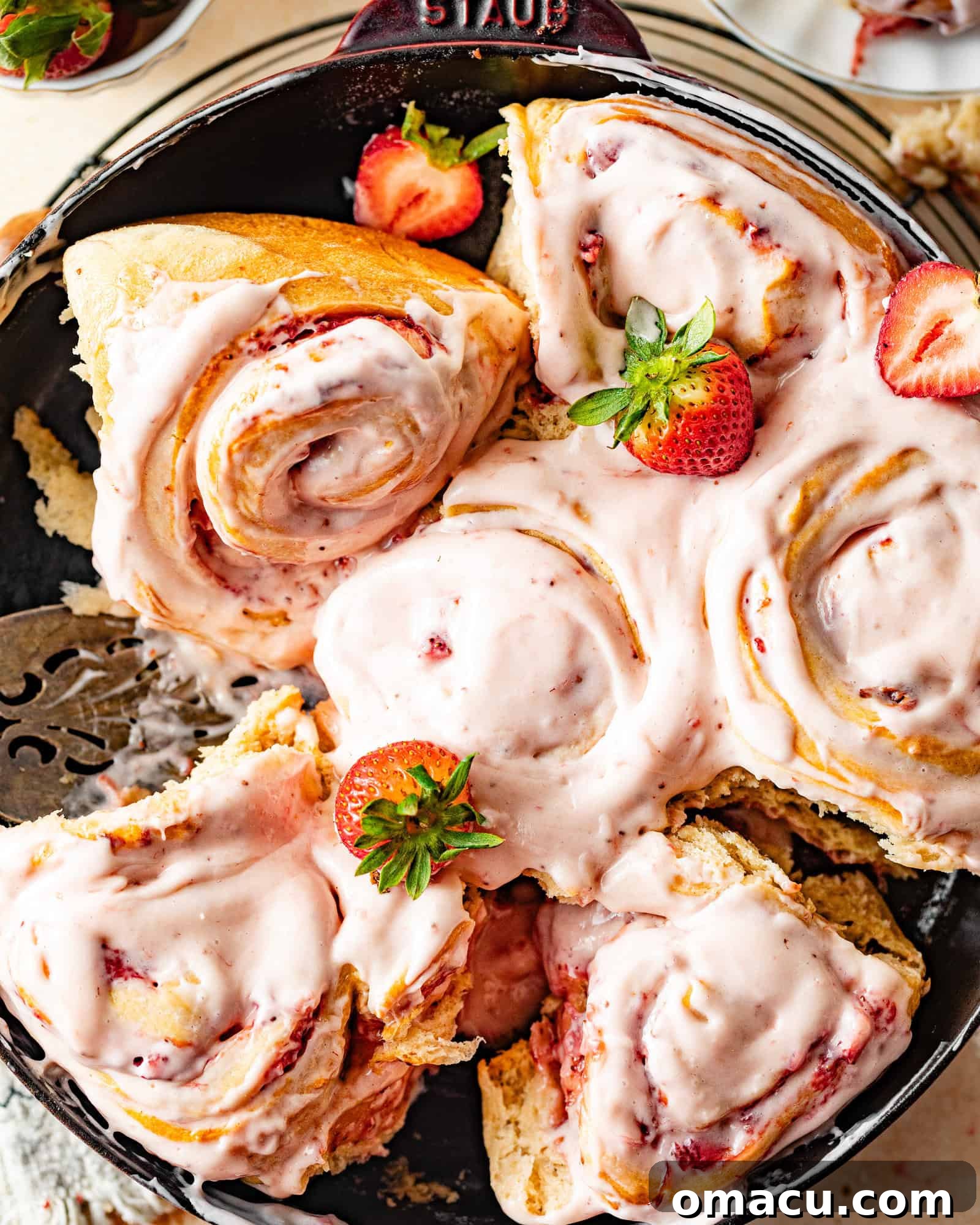 A baking pan filled with golden-brown strawberry cinnamon rolls, strategically turned to showcase their beautiful, gooey interior spirals and rich filling.