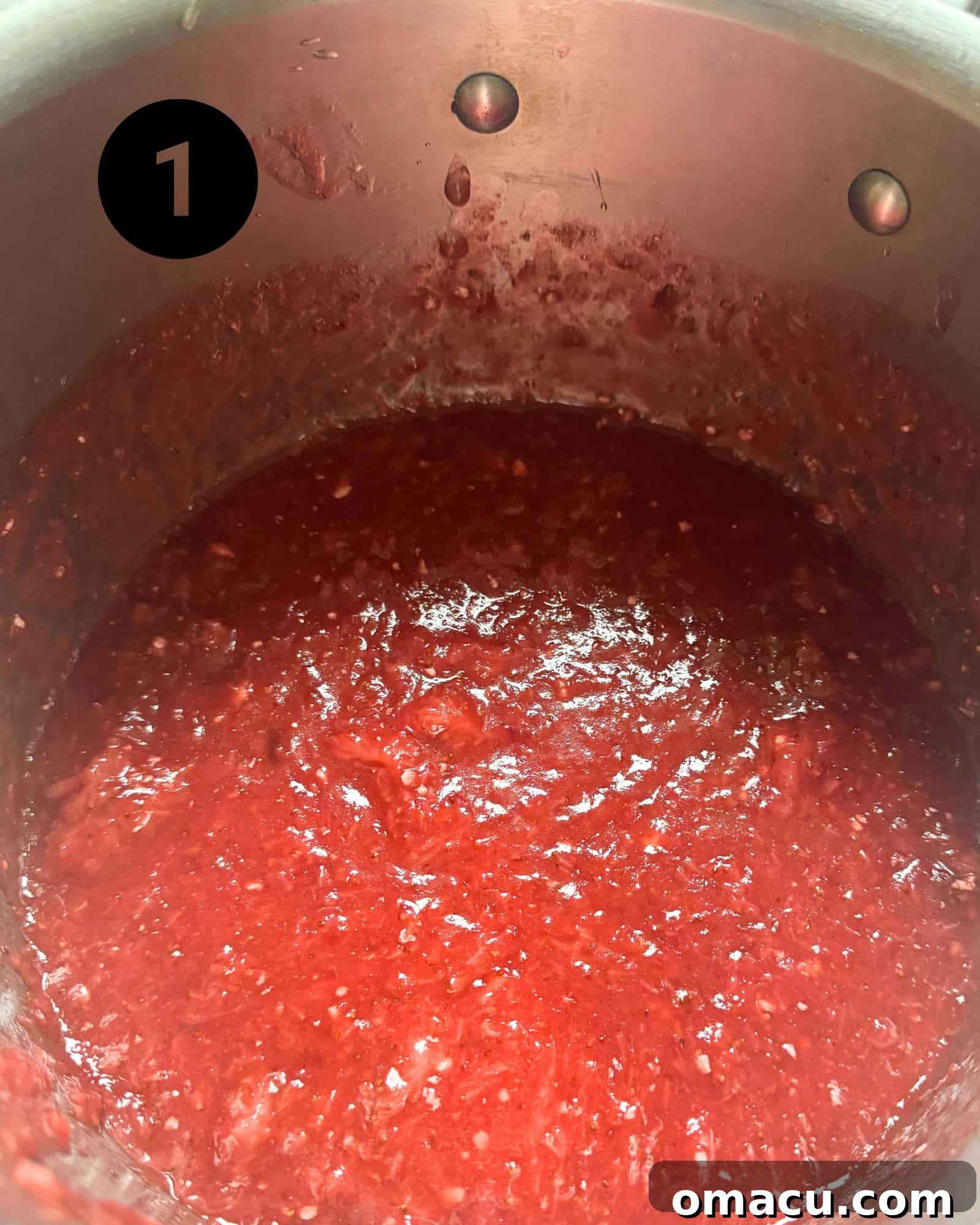 Freshly prepared strawberry filling simmering in a saucepan, showing its vibrant color and thickening consistency.