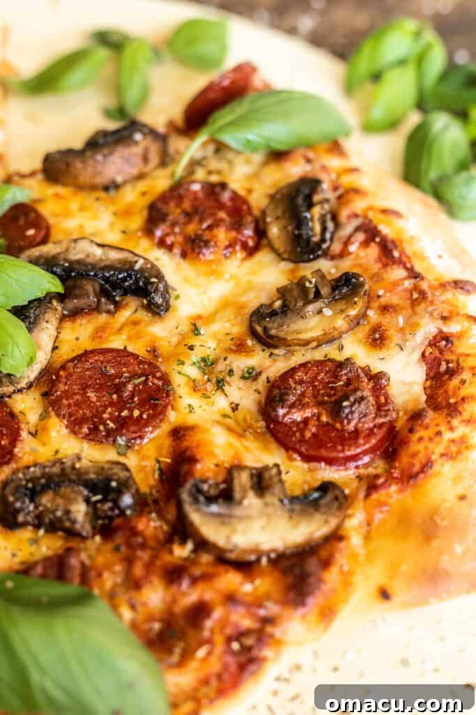 A close-up of a slice of the roasted mushroom and pepperoni pizza, showcasing the melted cheese and toppings.