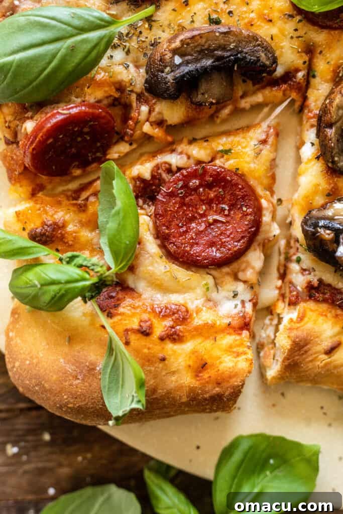 A hot slice of pepperoni pizza on a pizza stone, garnished with fresh basil leaves.