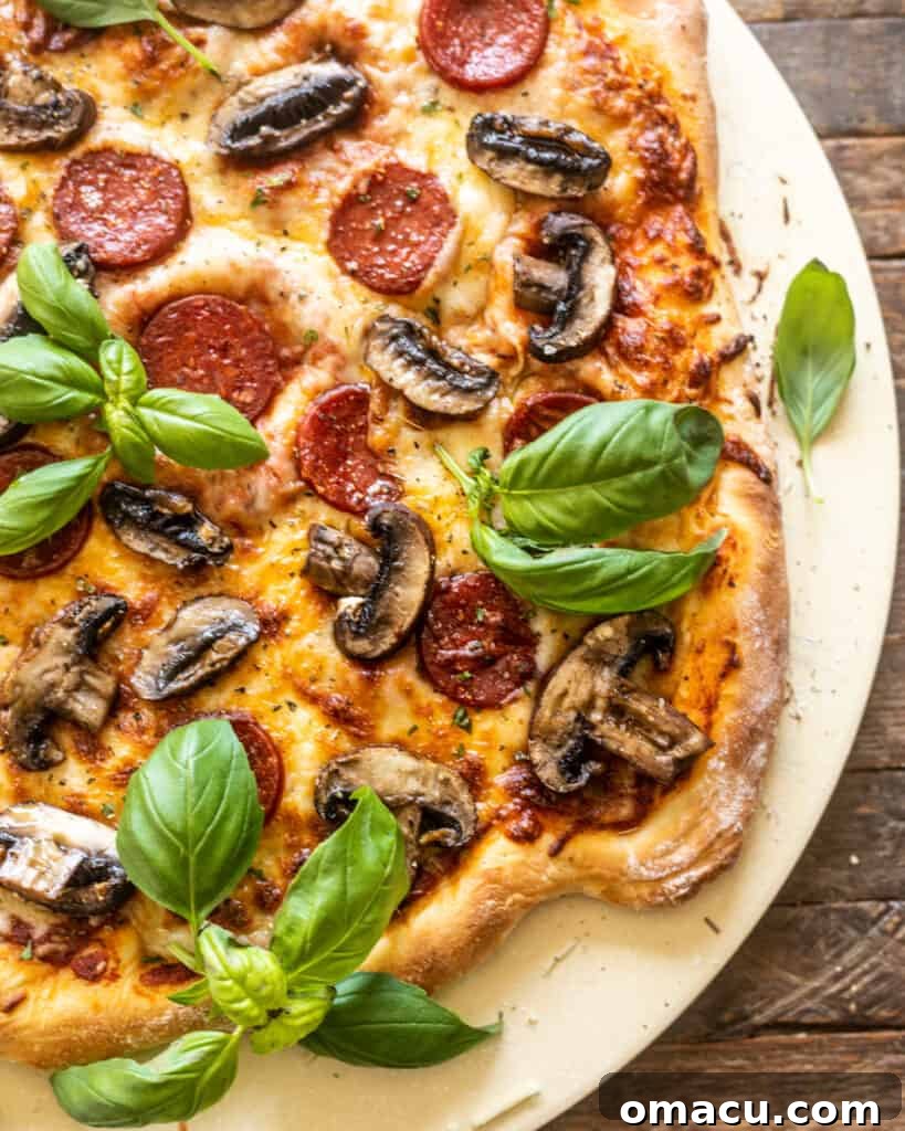A whole roasted mushroom and pepperoni pizza on a pizza paddle, ready to be served.