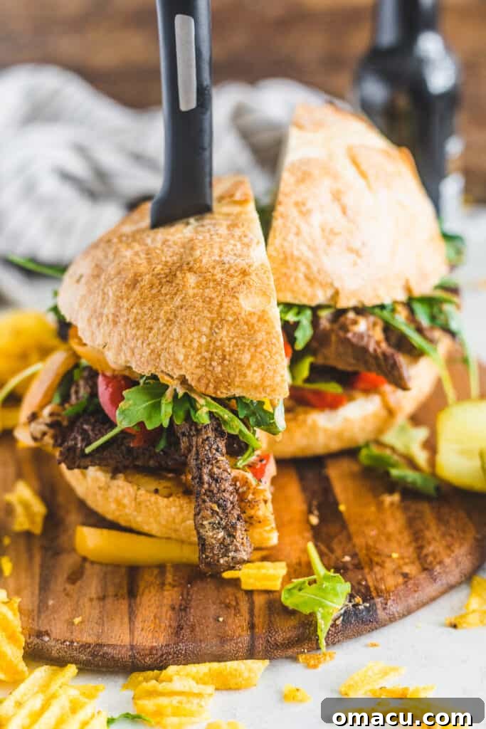 Close-up of a perfectly grilled Cajun steak sandwich, showcasing tender meat, colorful sautéed vegetables, and a creamy sauce on a rustic cutting board.