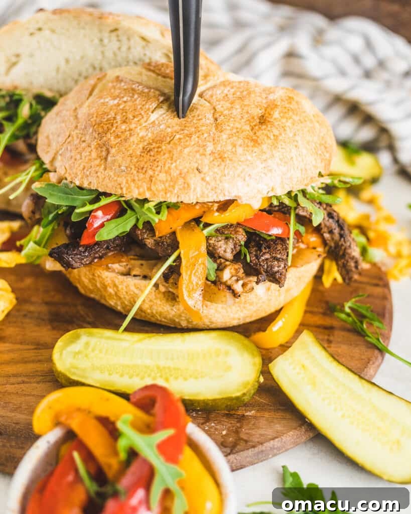 A freshly made Cajun steak sandwich cut in half, revealing layers of juicy steak, peppers, onions, and remoulade, ready to be enjoyed.