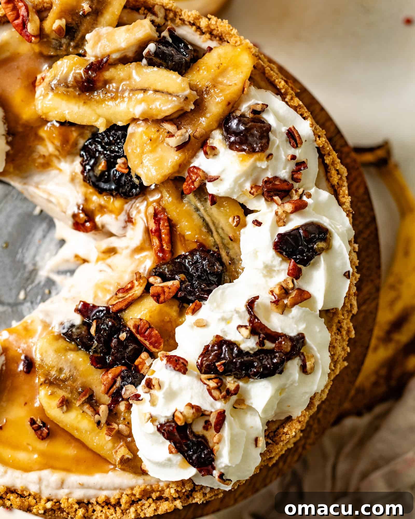 A stunning Bananas Foster Cheesecake, perfectly sliced and served on a cake stand, showcasing layers of creamy banana cheesecake, golden caramelized bananas and prunes, and a delicate swirl of cinnamon whipped cream, garnished with crunchy pecans. The rich, inviting colors hint at the decadent flavors within.