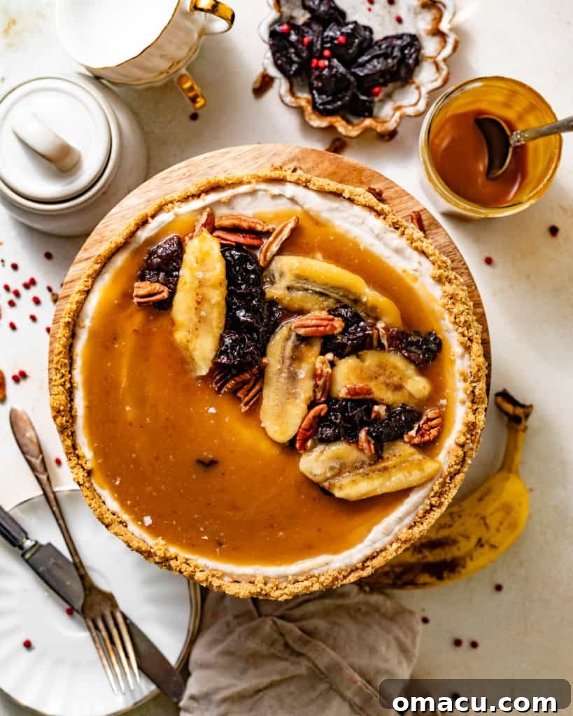 A stunning Bananas Foster Cheesecake sits on an elegant cake stand, adorned with caramelized bananas, prunes, and a cloud of cinnamon whipped cream, ready to be enjoyed. The rich textures and colors are visually appealing.
