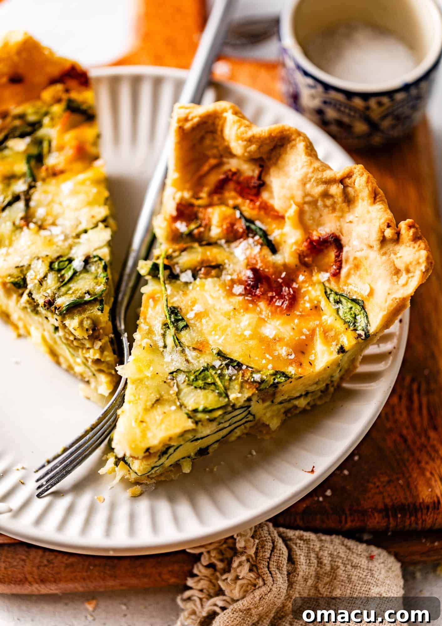 Two generous slices of Quiche Florentine served on a white plate, showcasing the vibrant green spinach and golden crust, accompanied by a fork.