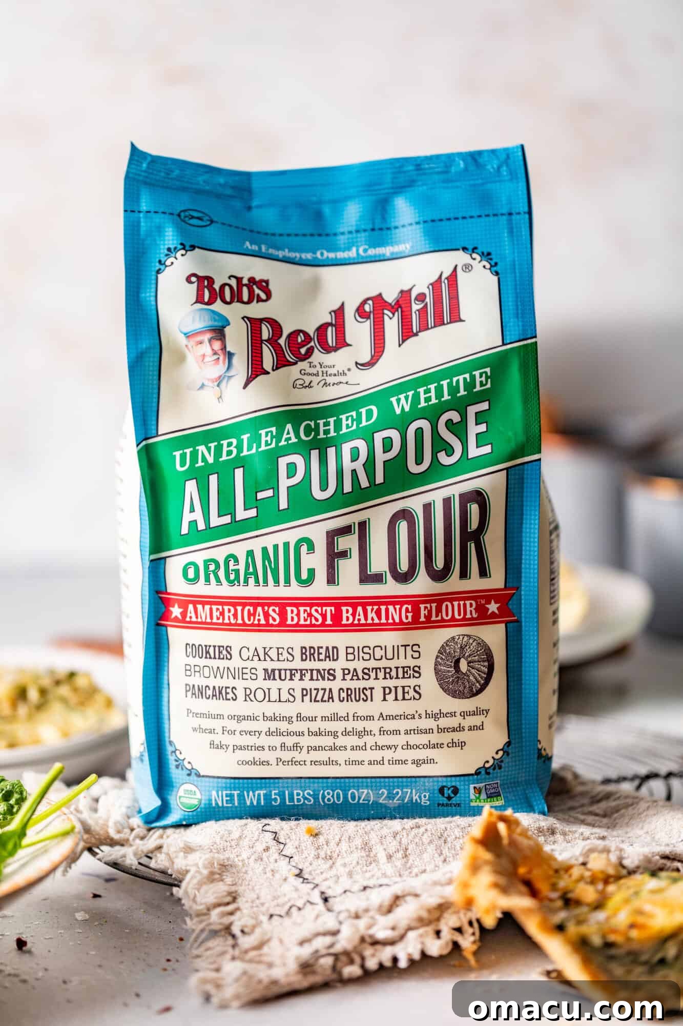 A bag of Bob's Red Mill all-purpose flour sits on a kitchen towel, highlighting a key ingredient.
