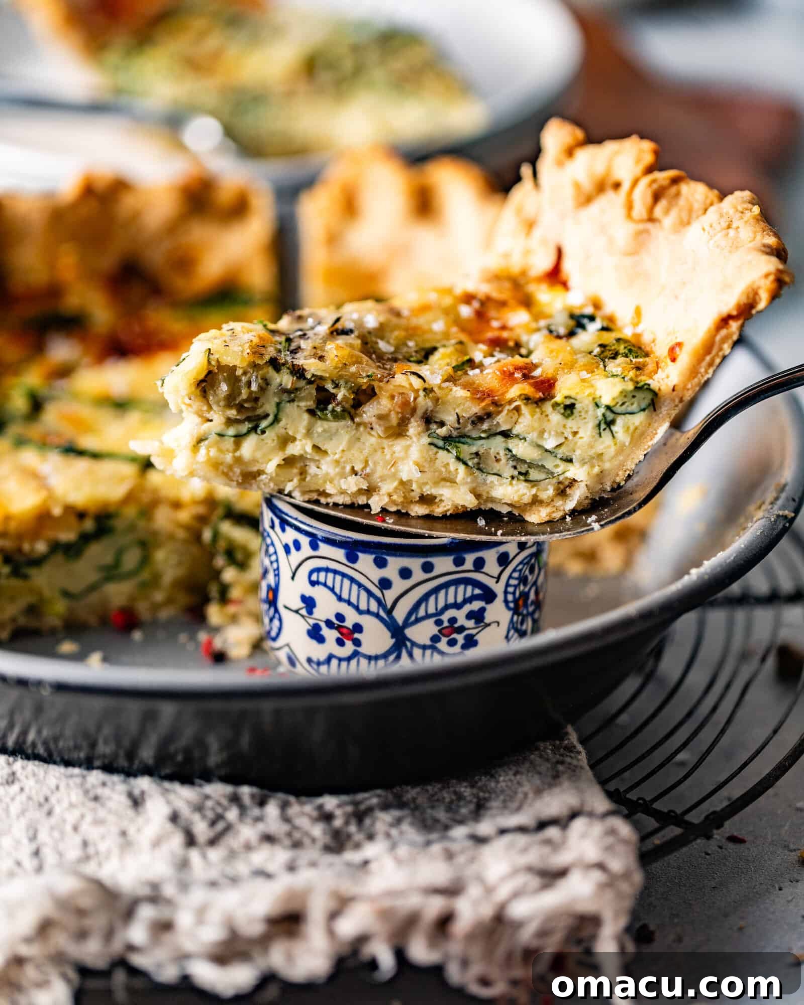 A slice of Quiche Florentine shown from a close-up angle, highlighting its layered filling and flaky crust.