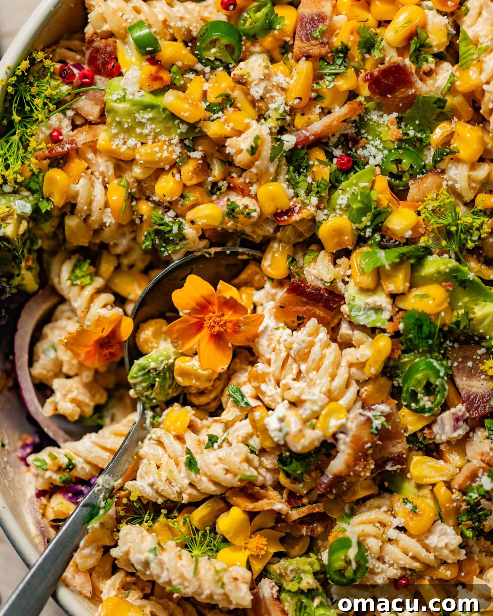 A bowl of Mexican street corn pasta salad, ready to be served with a spoon.