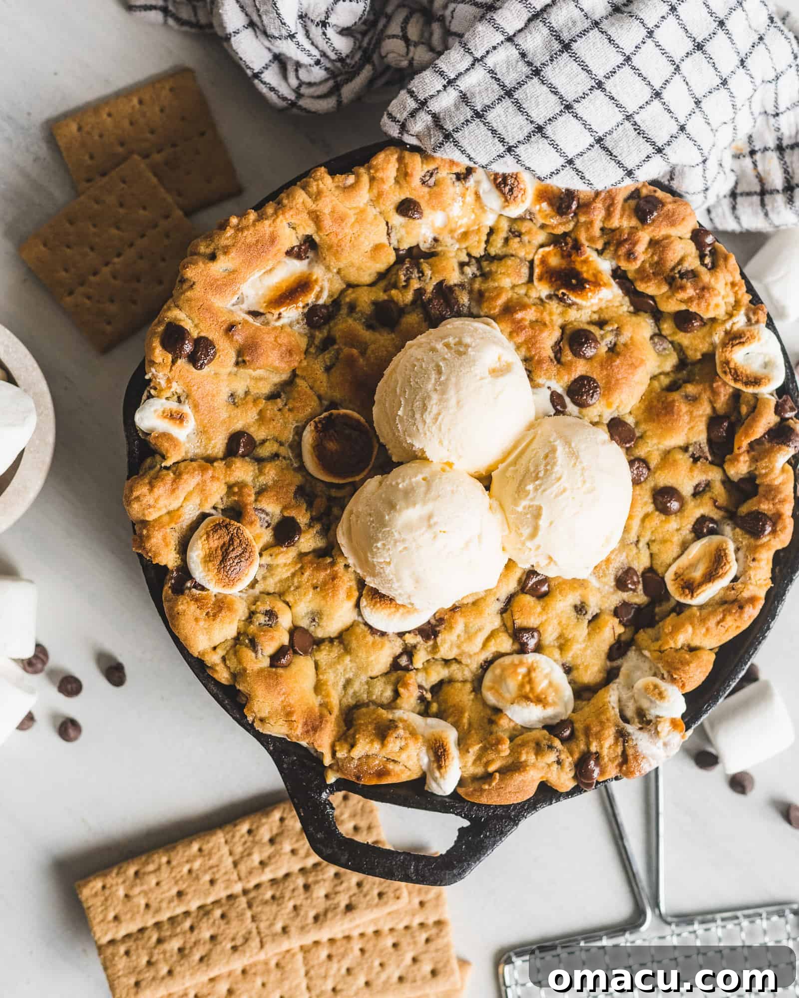 Scoop of ice cream melting on a warm S'mores Stuffed Chocolate Chip Skillet Cookie, highlighting the gooey s'mores filling.