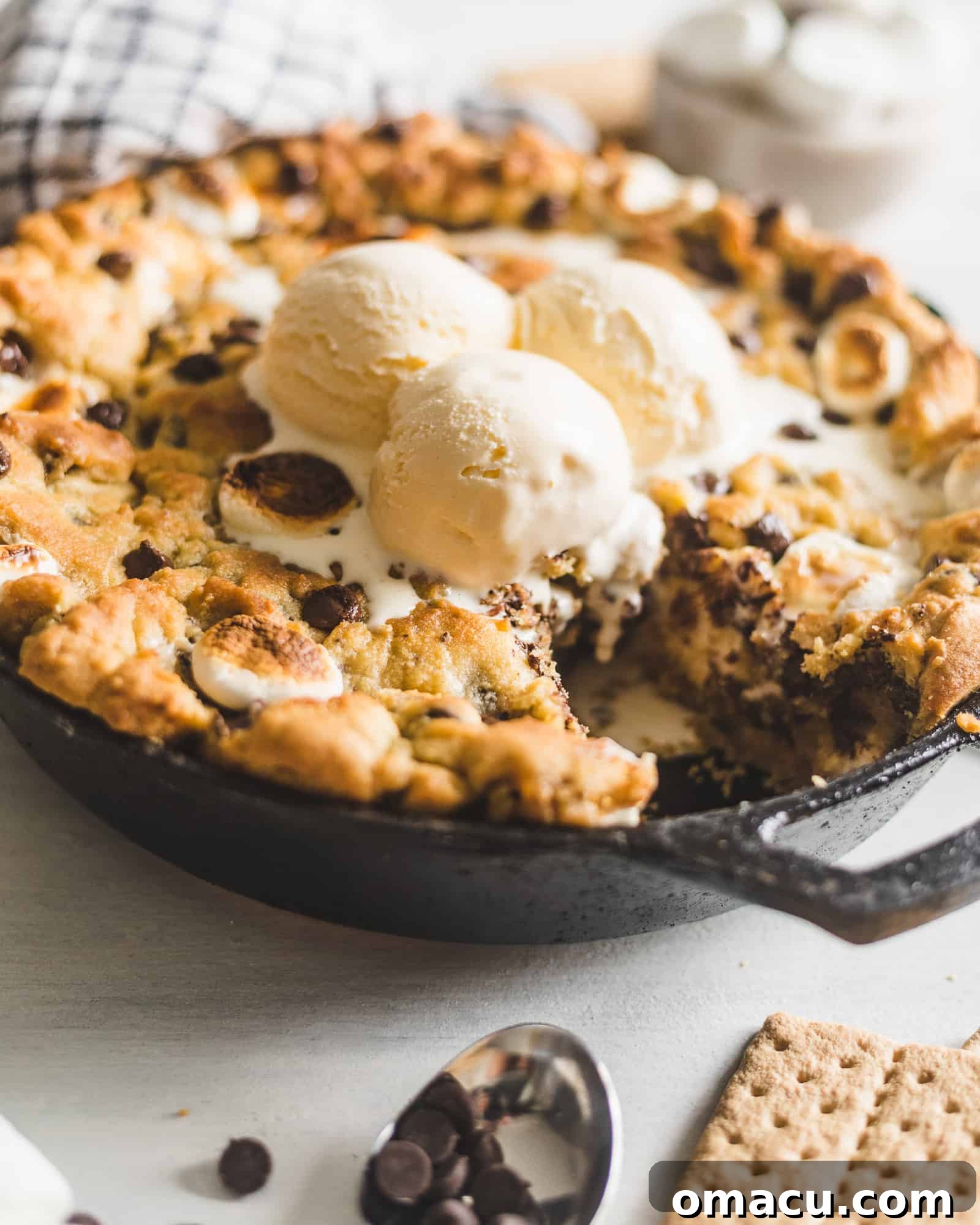 S'mores Stuffed Chocolate Chip Skillet Cookie cooling in a cast iron skillet, with a slight golden brown crust.