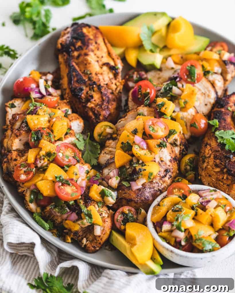 Honey Garlic Chicken topped with fresh peach salsa on a white plate with green herbs