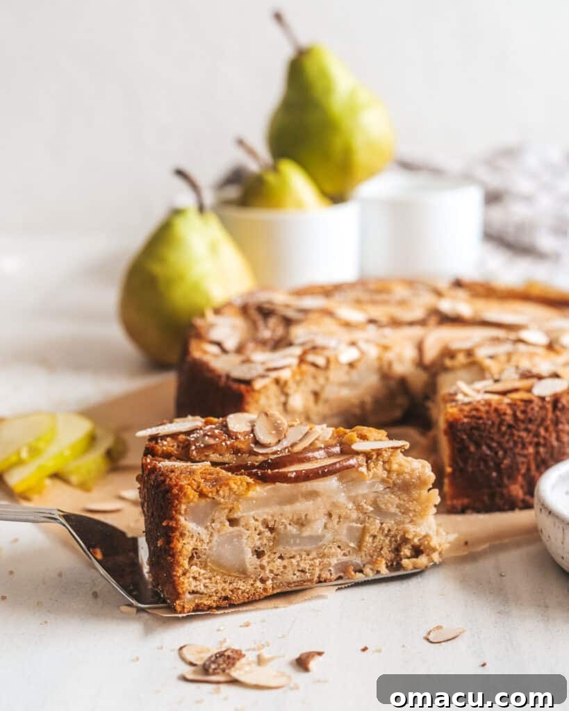 A close-up of a slice of Spiced Pear and Almond Cake, showing the soft, moist interior with visible chunks of pear and a hint of spice.