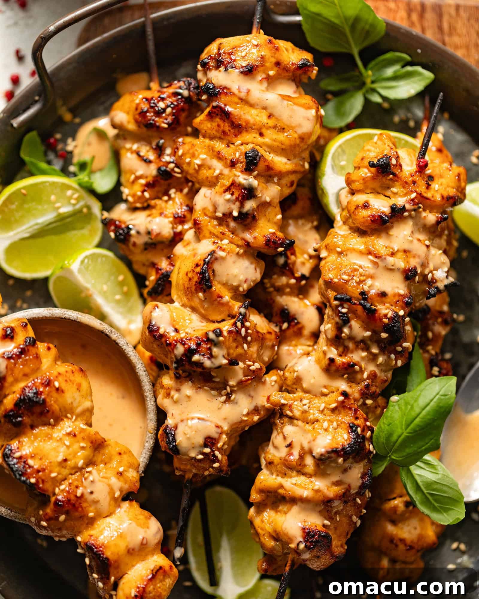 Bang Bang Chicken Skewers on a metal plate garnished with fresh basil and lime slices.