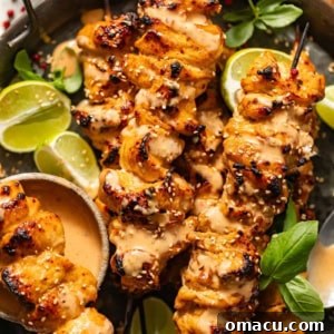 Bang Bang Chicken Skewers on a metal plate garnished with basil and lime slices.