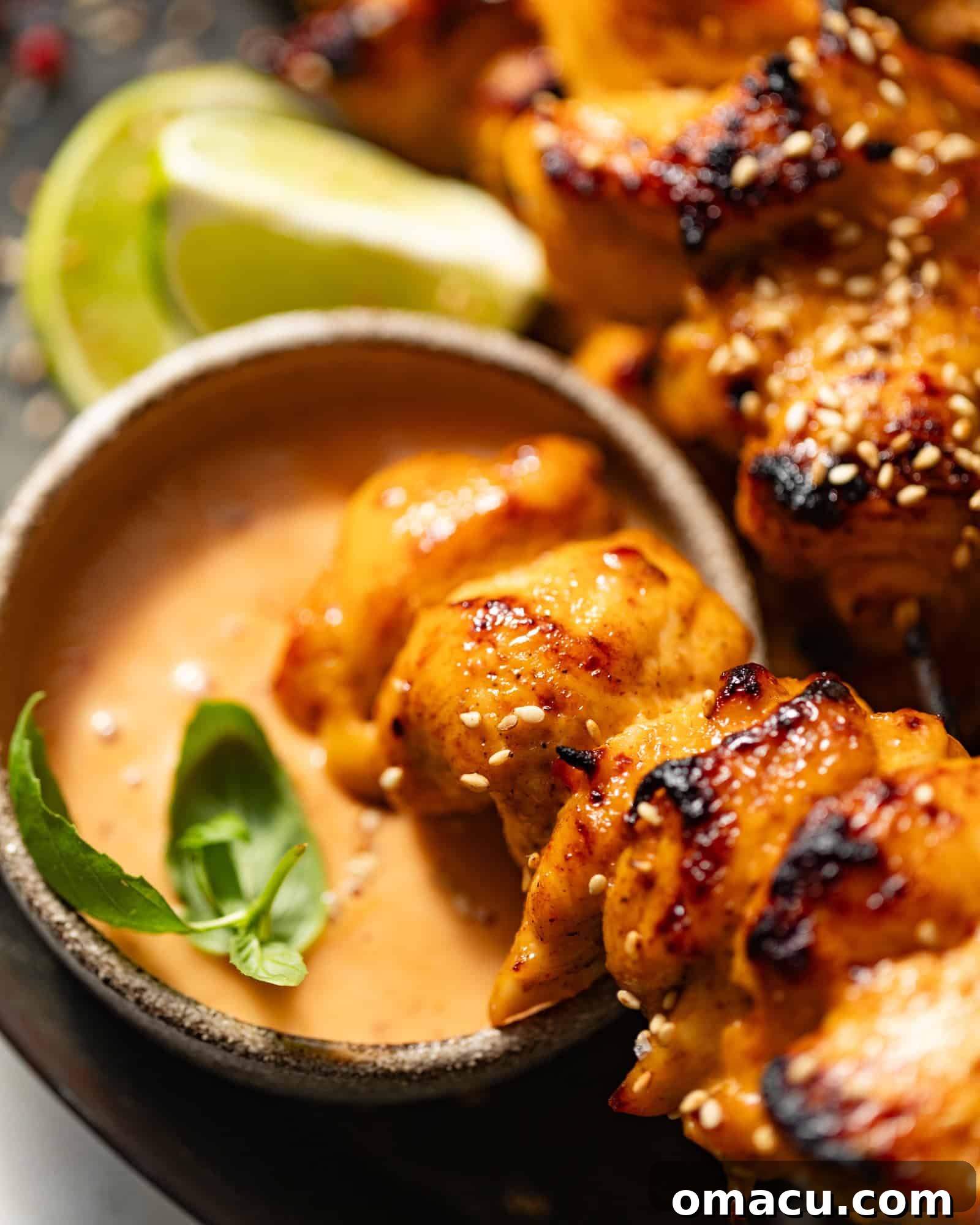 A chicken kebab being dipped in bang bang sauce.