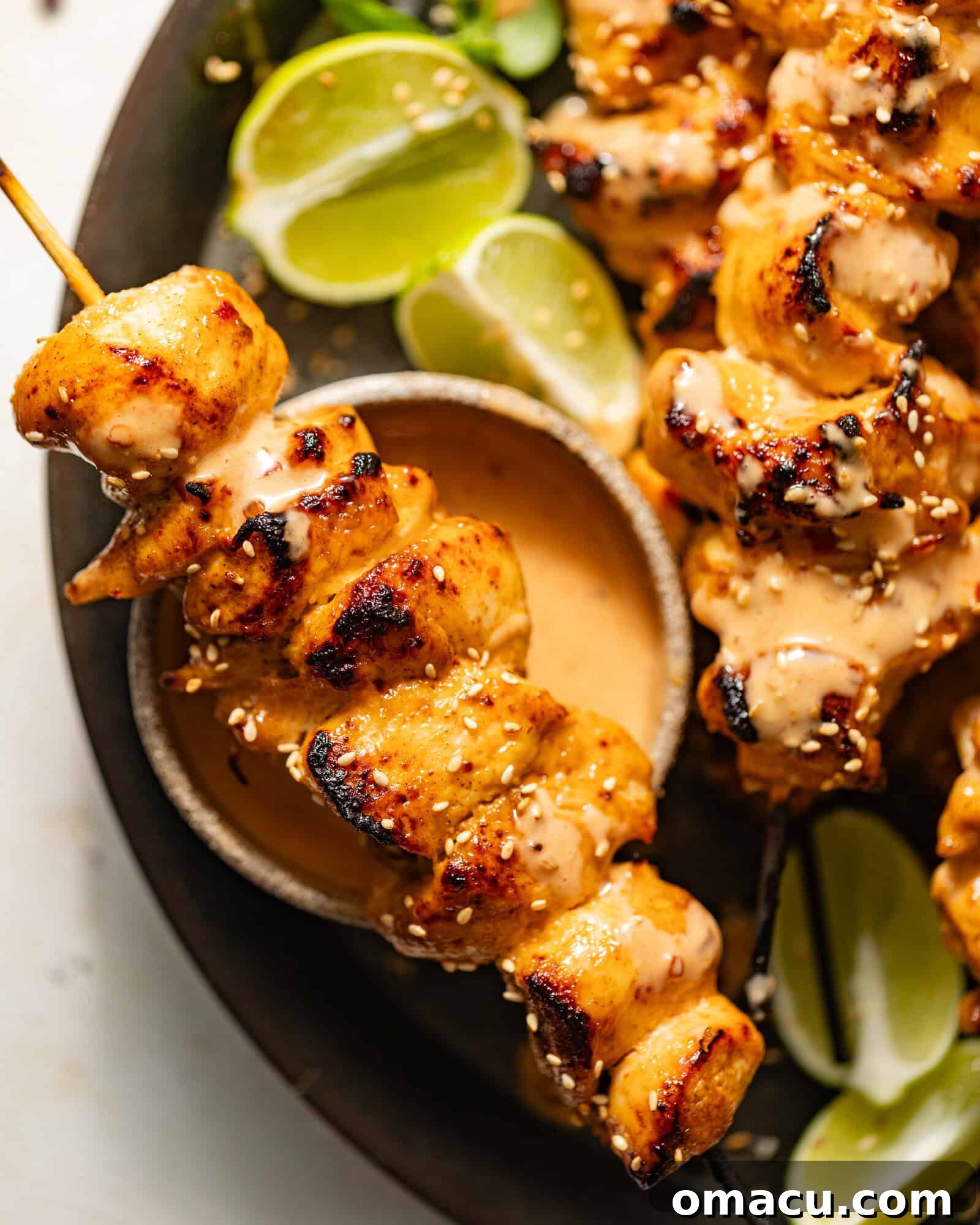 A bang bang chicken skewer on top of a bowl of bang bang sauce.
