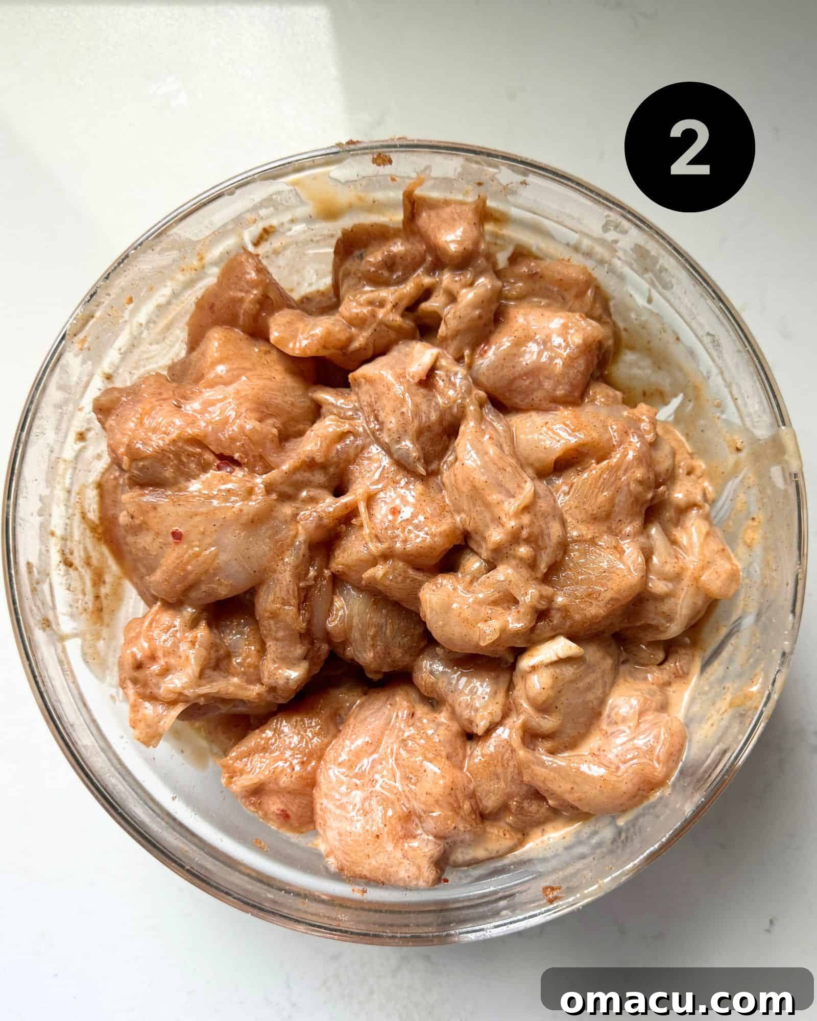 Cut up chicken pieces in a bowl coated in seasonings and bang bang sauce.