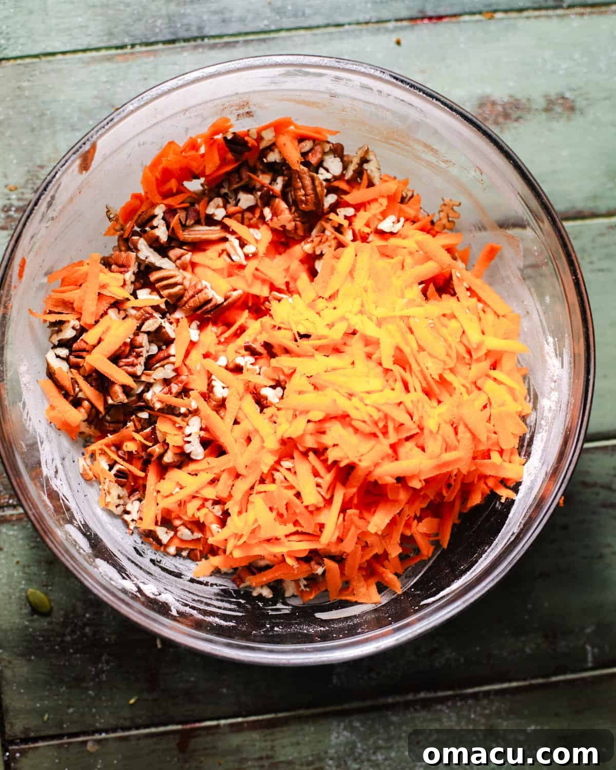 Grated carrots and pecans in a bowl.