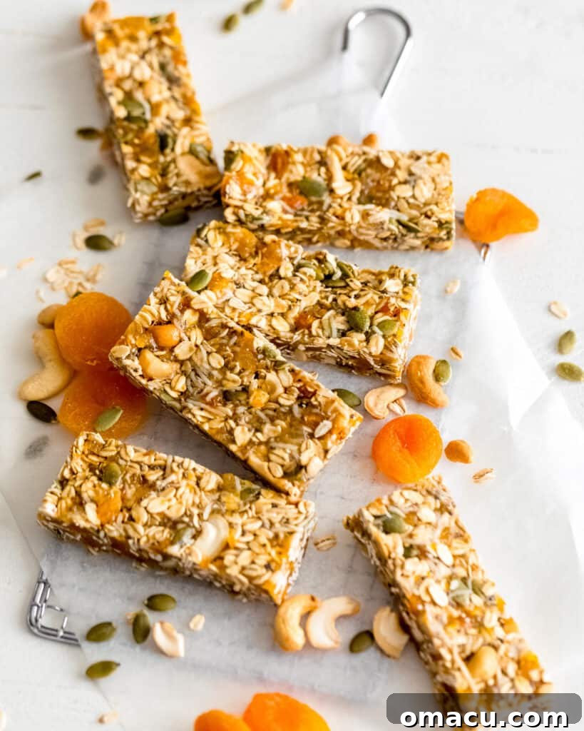 Apricot Coconut Cashew bars arranged neatly on a white surface, garnished with scattered dried apricots and pumpkin seeds, showcasing their wholesome texture.