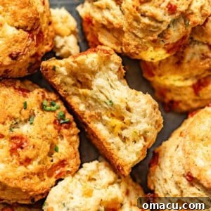 up close photo of cheddar biscuits with chives on a serving tray with one biscuit with a bite taken out of it.