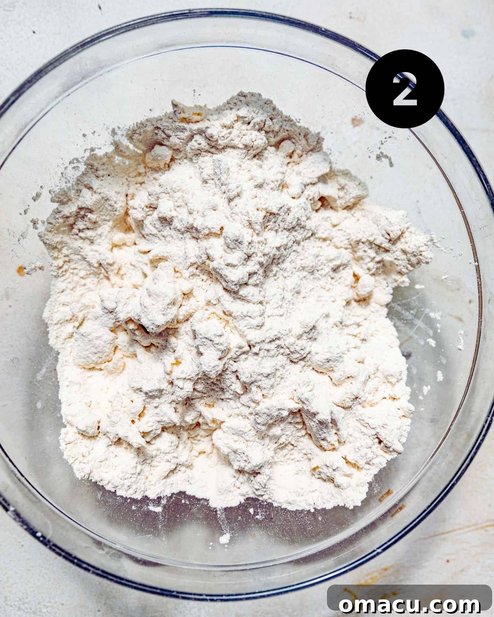 grated butter combined with dry ingredients in a mixing bowl.