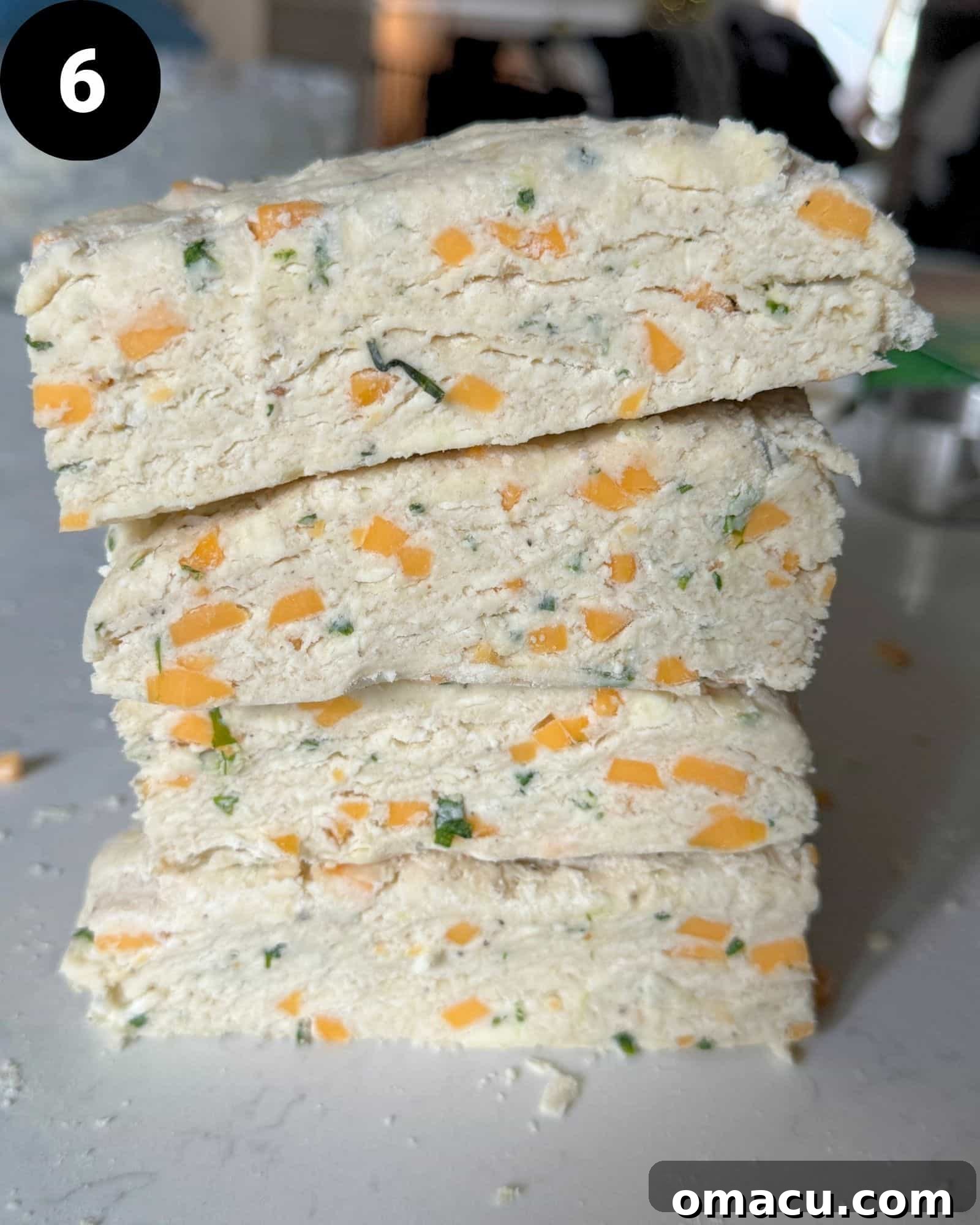 biscuit dough cut into four pieces and stacked on top of itself.
