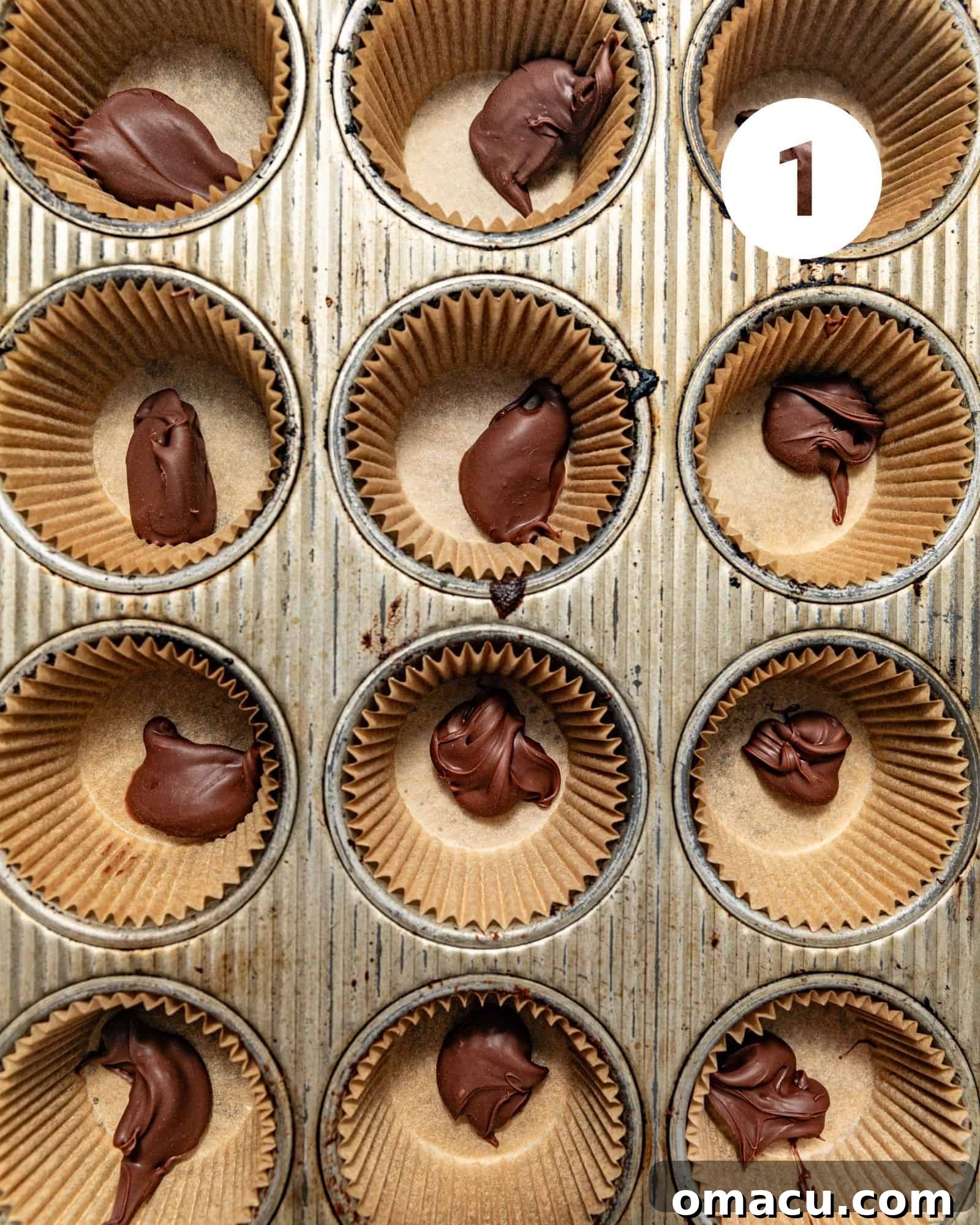 A close-up shot of a muffin pan with cupcake liners, each filled with approximately one tablespoon of Nutella, ready for freezing.