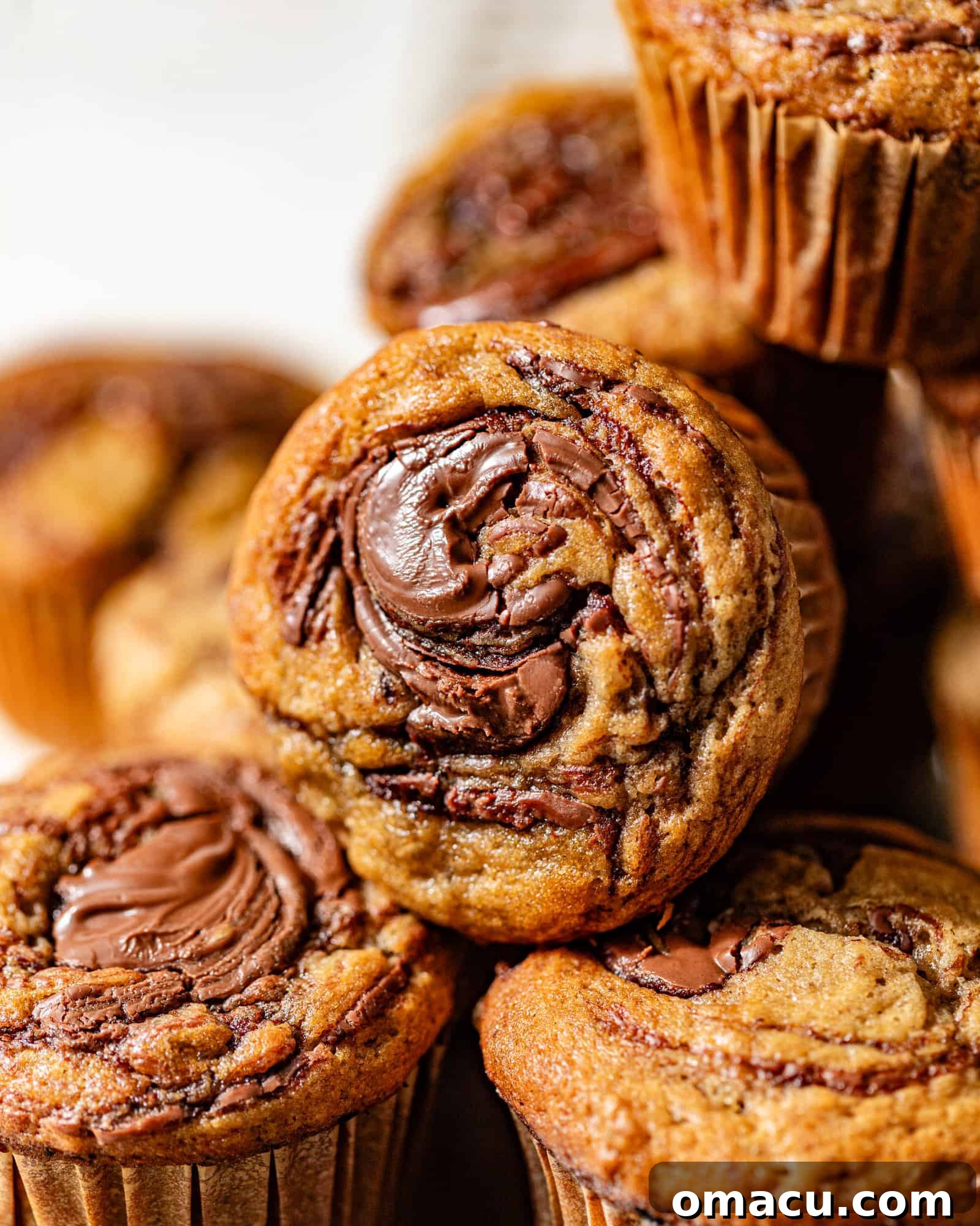 Three perfectly baked banana Nutella muffins stacked on top of each other, highlighting their moist texture and golden-brown tops.
