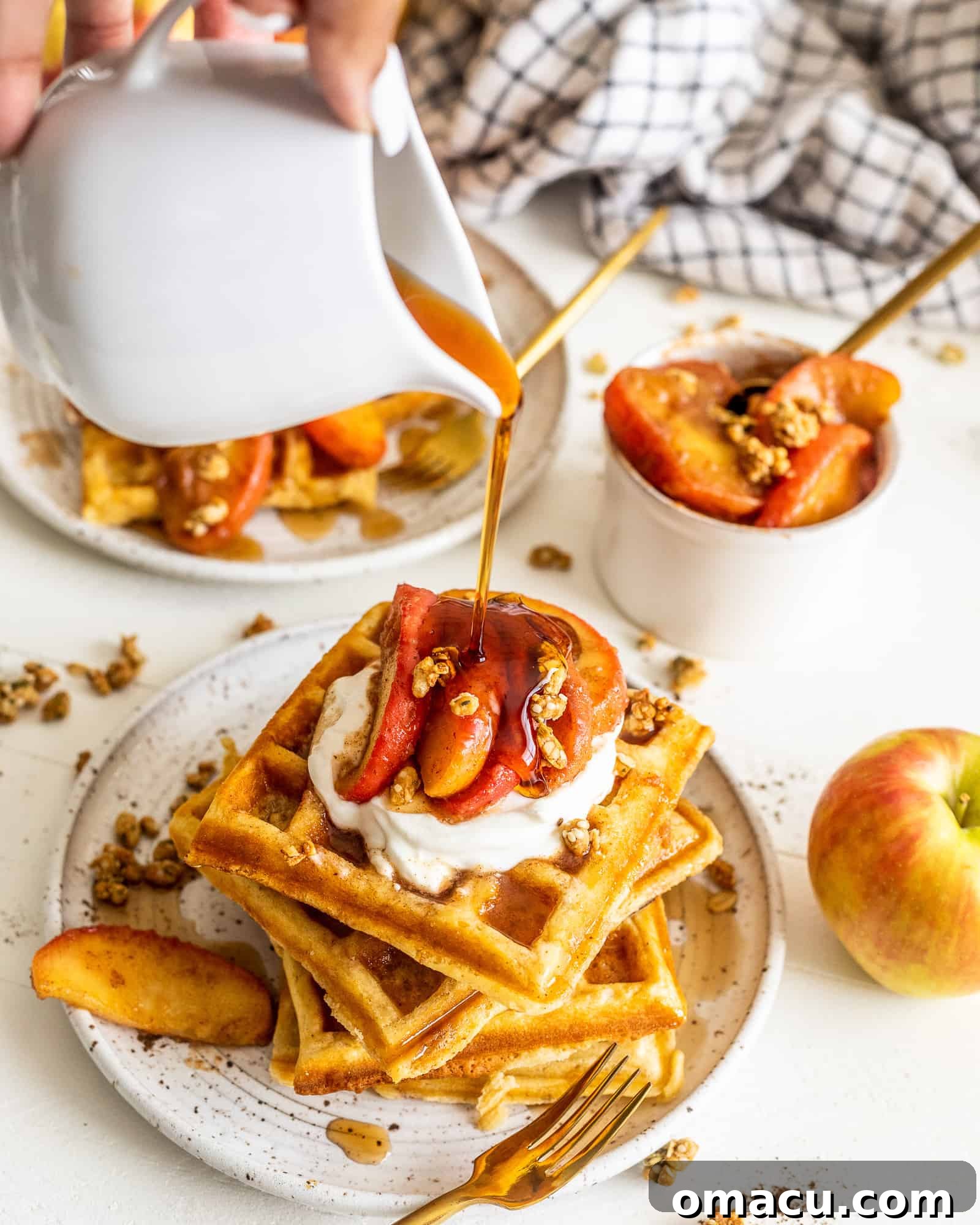 Pouring syrup on top of waffles with cinnamon apples