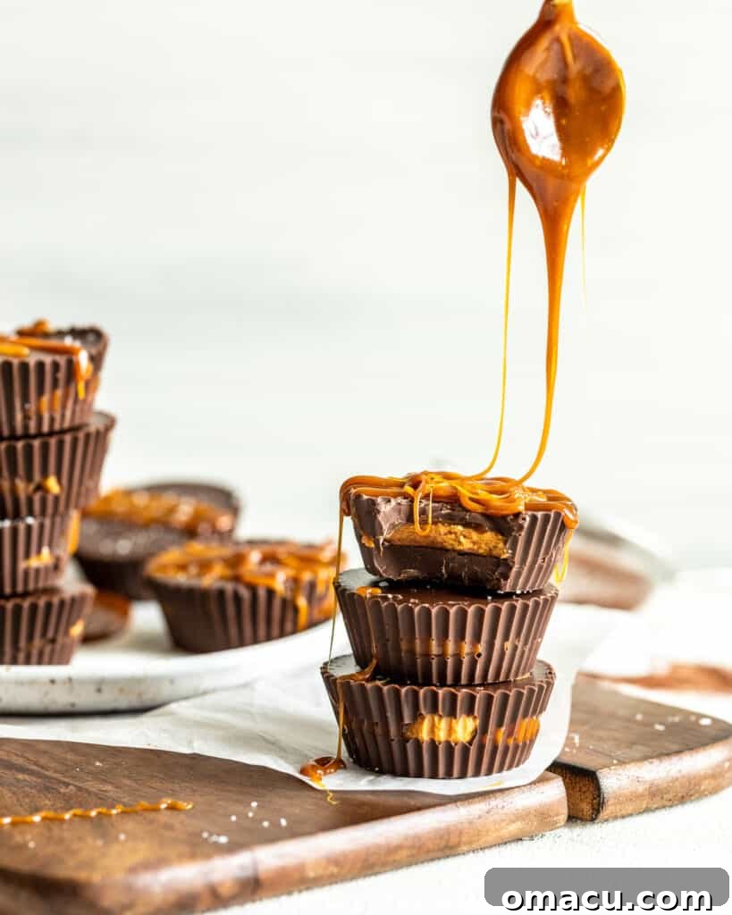 Salted caramel being delicately spooned onto the creamy peanut butter filling within the prepared chocolate cups.