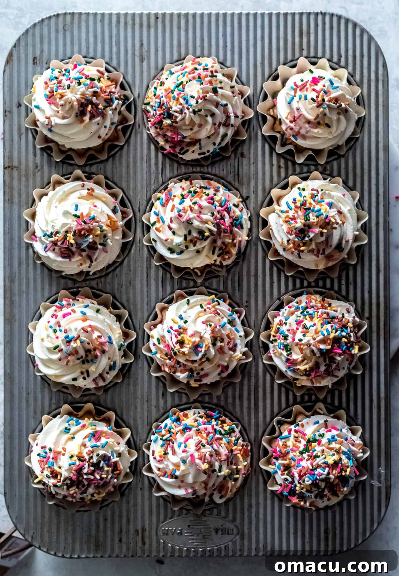 A perfectly frosted Funfetti Cupcake, ready to be enjoyed, showcasing the soft texture of the cake and the creamy almond buttercream.