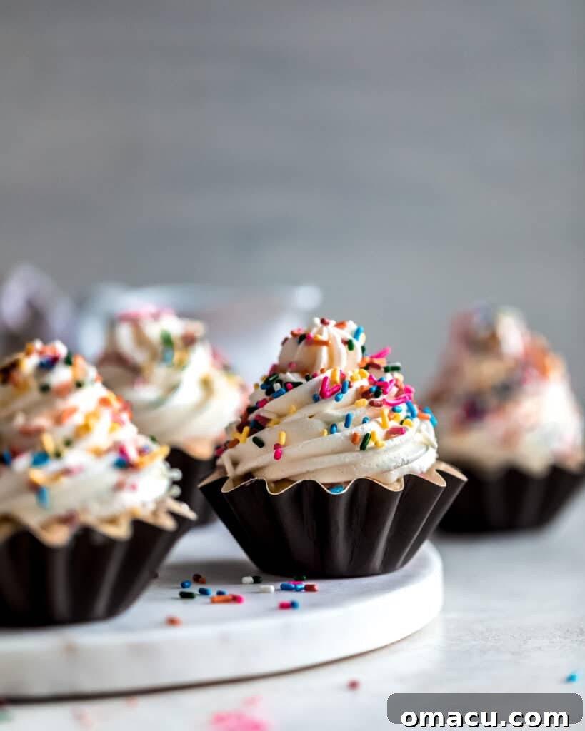 A frontal view of several Funfetti Cupcakes with sprinkles on top, elegantly displayed on a marble cutting board, inviting you to take a bite.