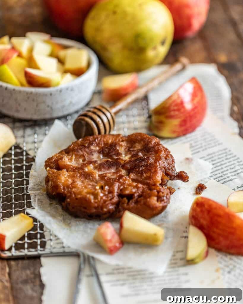 Photo of a single apple pear fritter on a piece of parchment paper, showcasing its crispy exterior and glaze.