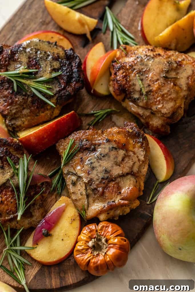 An overhead shot of a carving board with a knife, featuring slices of the tender Rosemary Apple Cider Chicken.