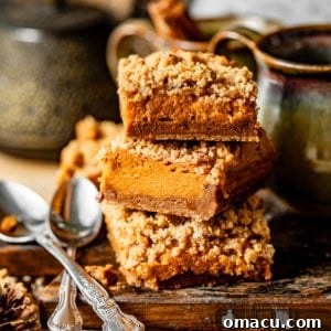 Sweet potato pie bars stacked on top of each other on a wooden board, showcasing their rich layers.