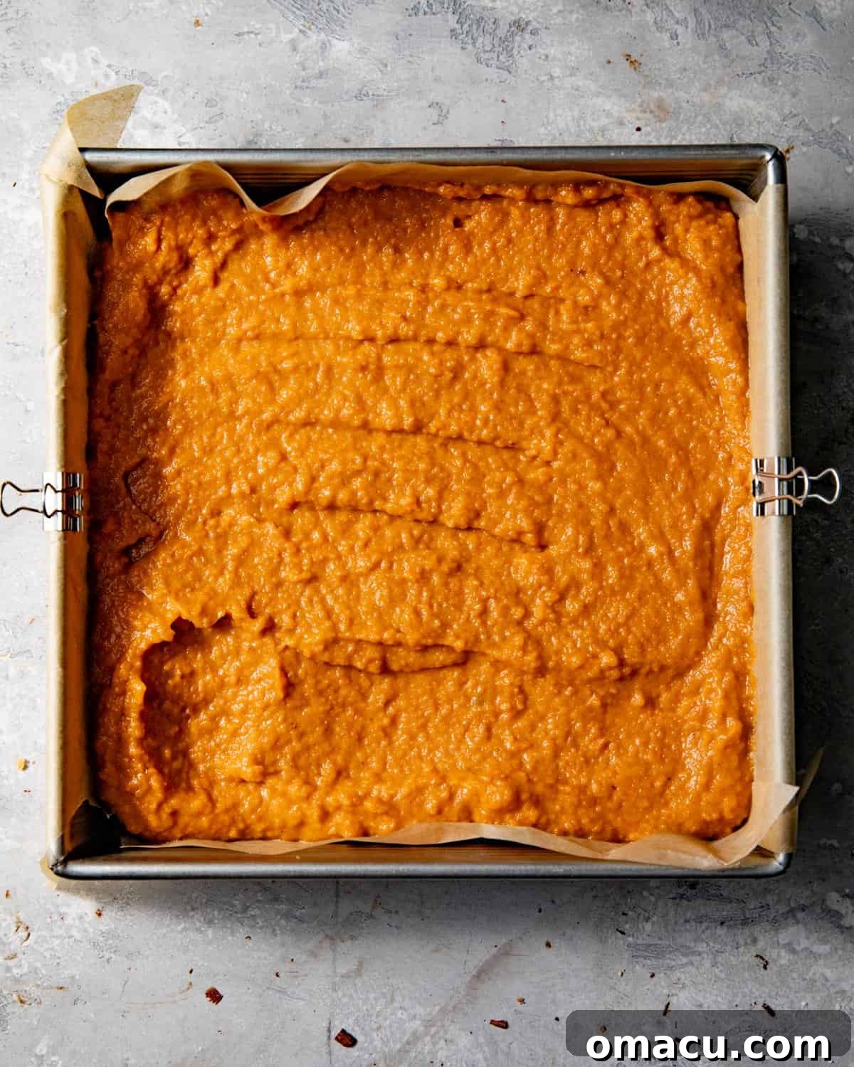 Sweet potato pie filling poured over the baked Biscoff crust in a square baking pan.