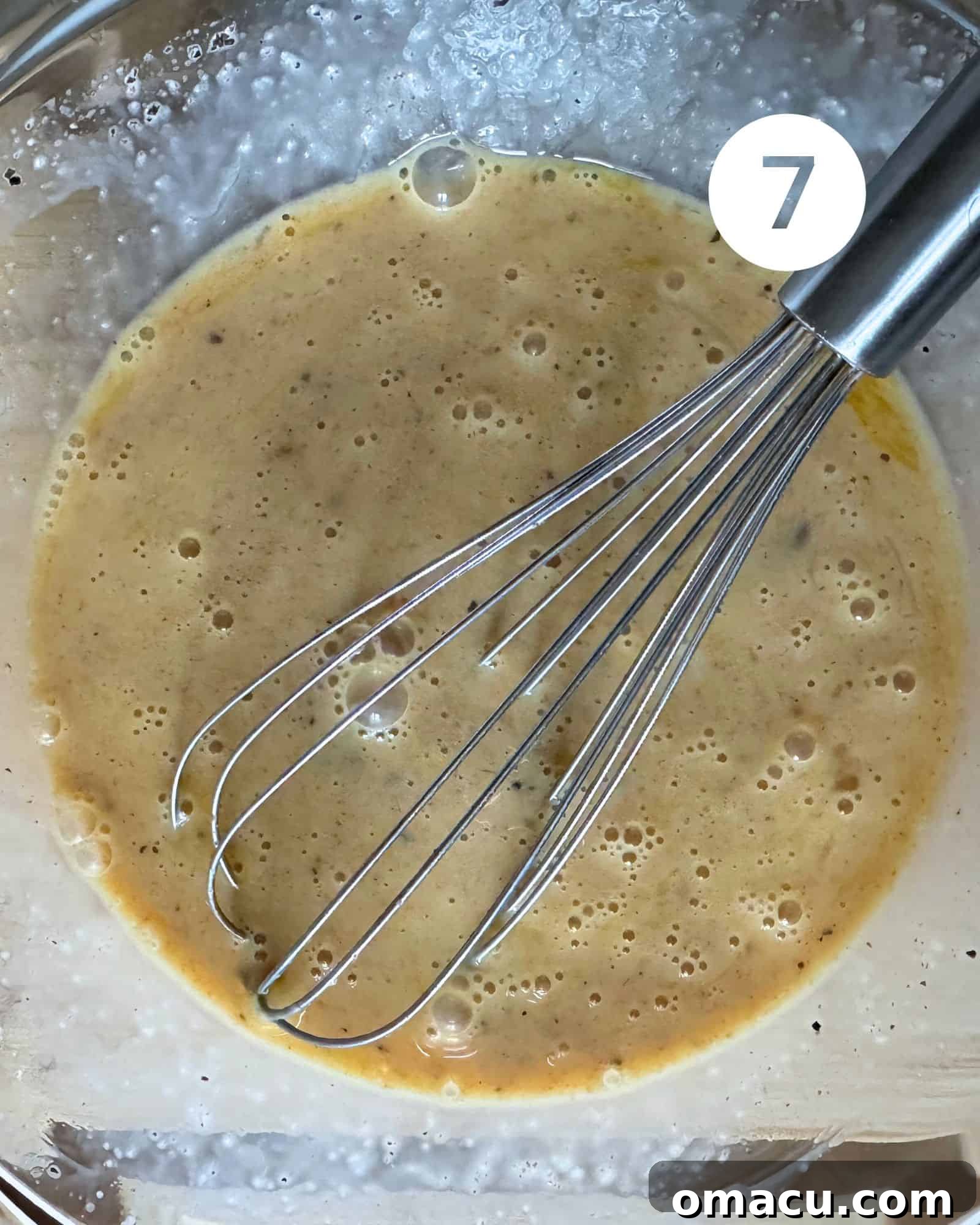 A creamy, whisked custard mixture for the quiche filling in a mixing bowl, showing its smooth consistency before being poured into the crust.