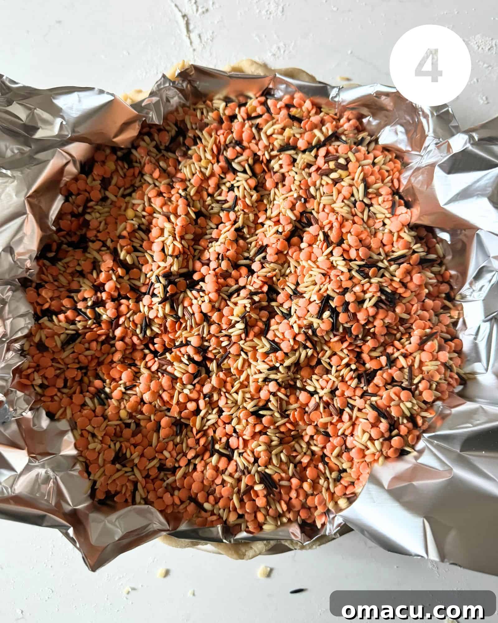 Unbaked pie dough nestled in a pie dish, filled with pie weights and lined with parchment paper, prepared for blind baking.
