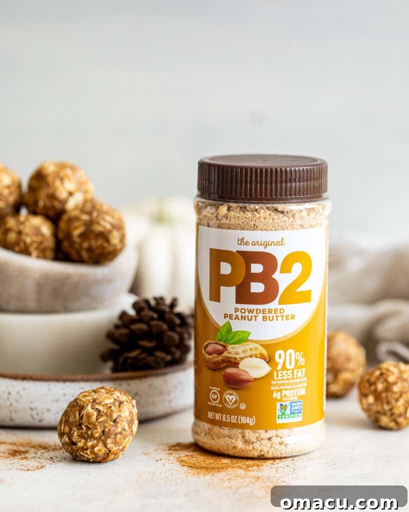 Close-up photo of chai spiced energy bites in a bowl, with a container of PB2 powdered peanut butter clearly visible in the background, emphasizing a key ingredient.