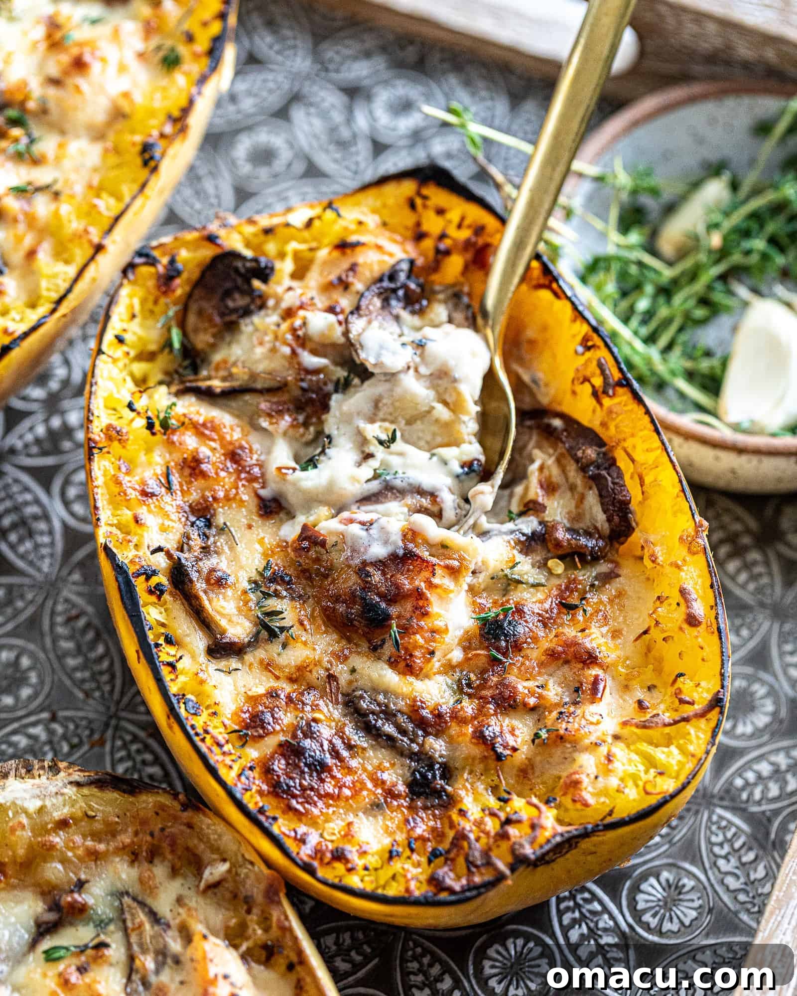 Two halves of roasted spaghetti squash on a baking tray, garnished with fresh herbs and a drizzle of olive oil, ready to be filled.