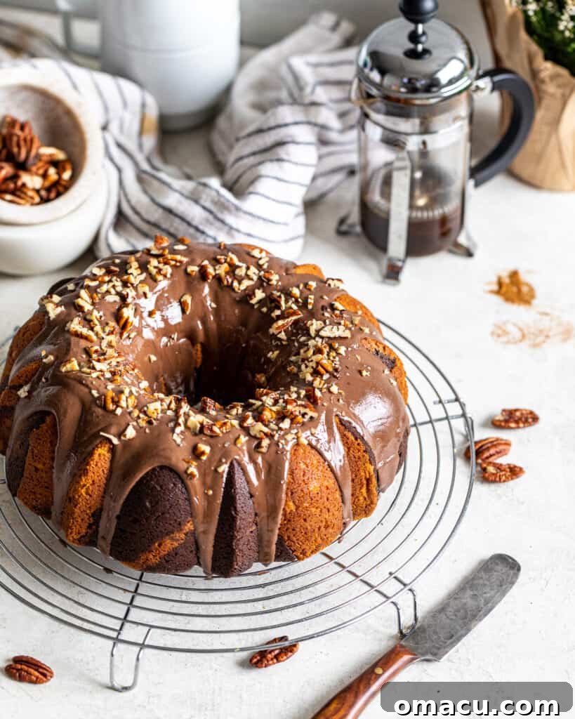 A freshly baked chocolate coffee marble cake cooling on a wire rack, with a French press coffee maker in the background, suggesting its rich coffee flavor.