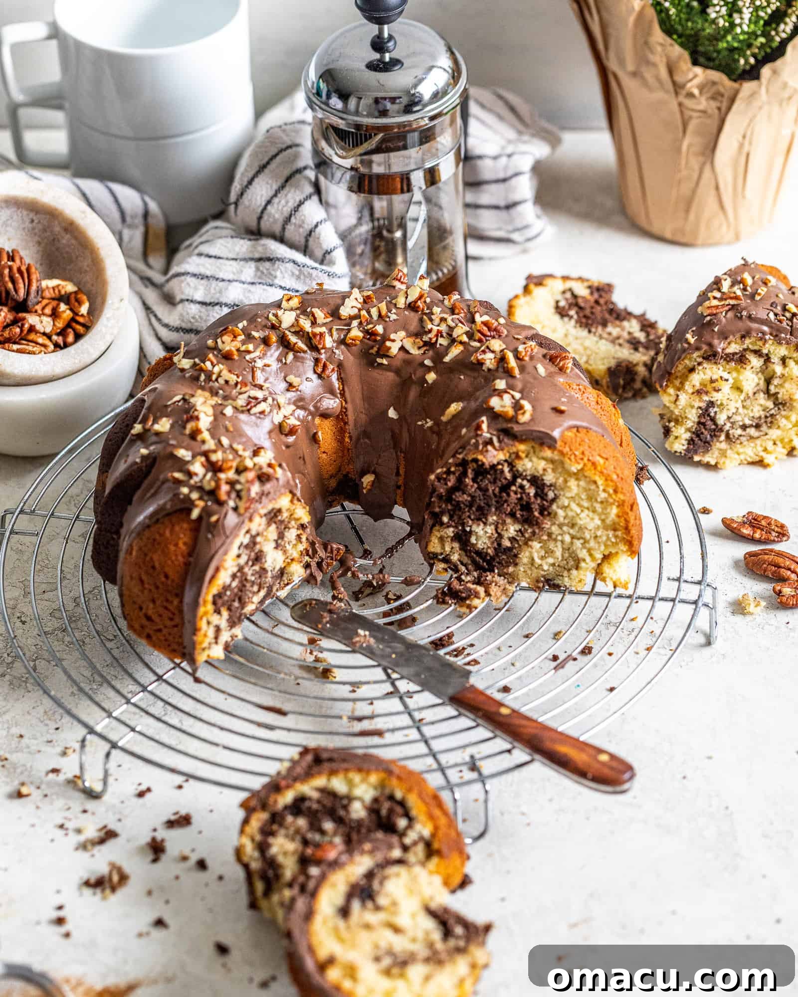 A beautifully sliced chocolate coffee marble cake displayed on a table next to a French press, inviting guests to enjoy a perfect pairing.