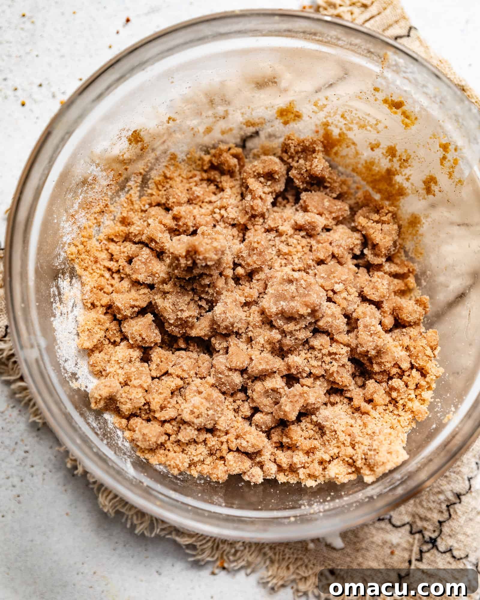 Close-up of the buttery, spiced crumb topping mixture in a bowl, showing its ideal texture before being chilled.