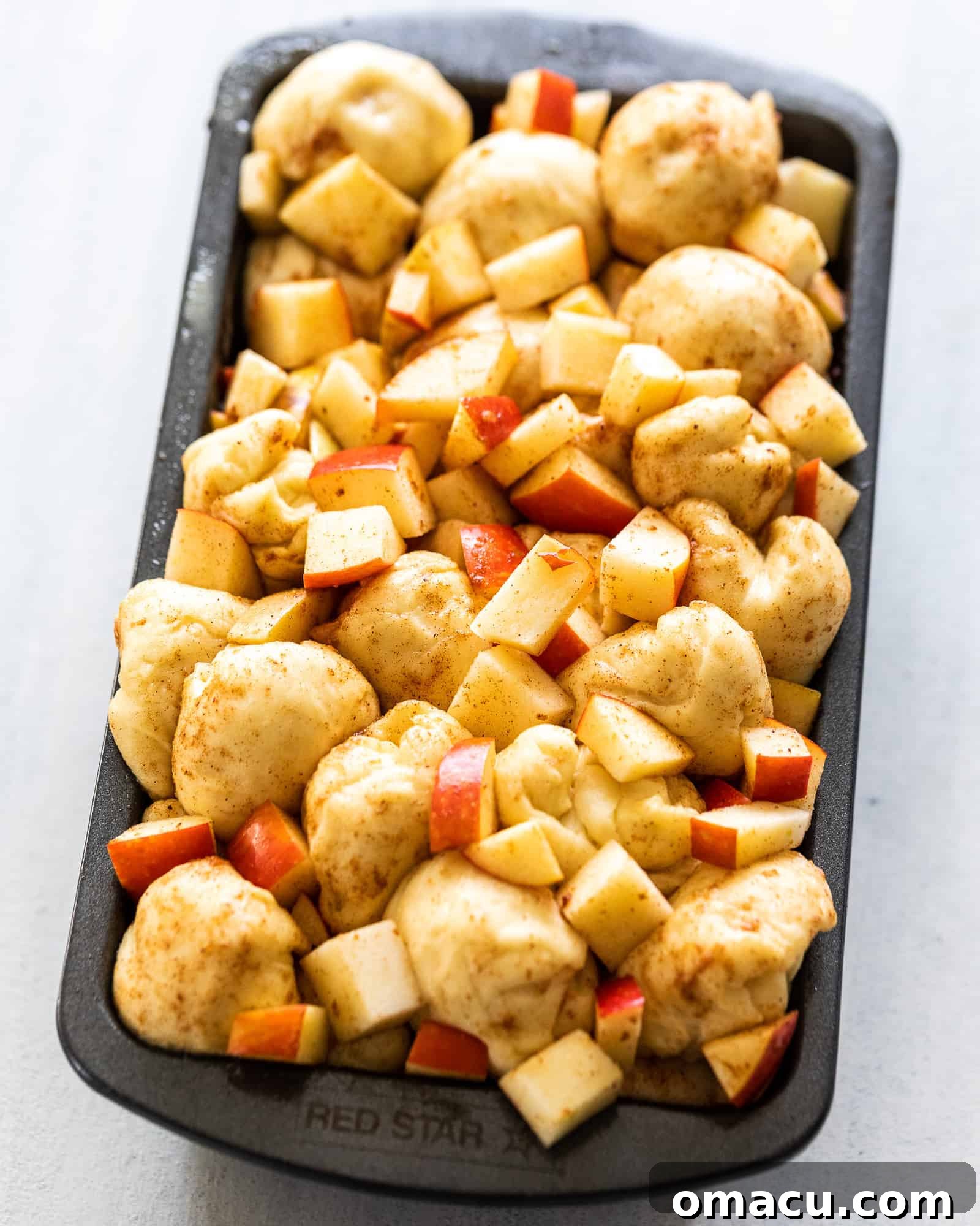 Unbaked Apple and Pear Bread dough balls mixed with fruit in a loaf pan, ready for the oven