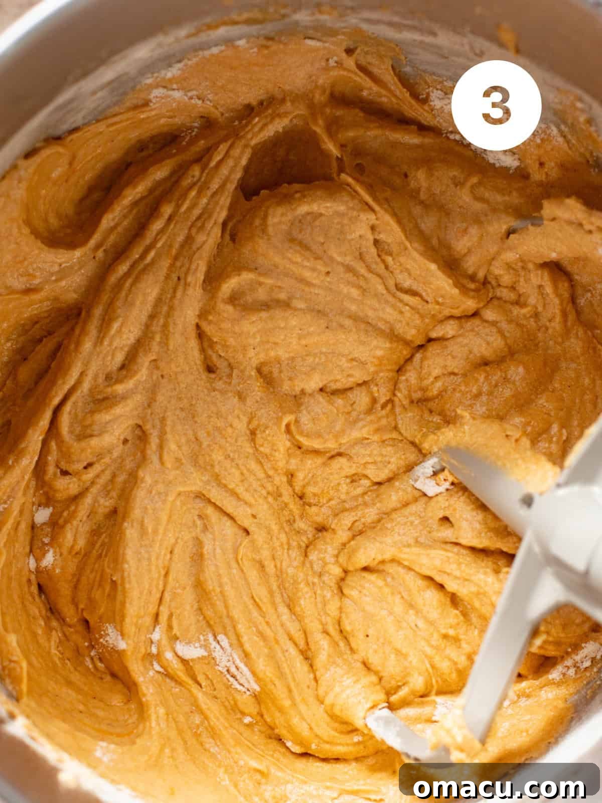Butter, mashed sweet potatoes, brown sugar, granulated sugar, and eggs mixed together in a stand mixer bowl, forming a rich batter.